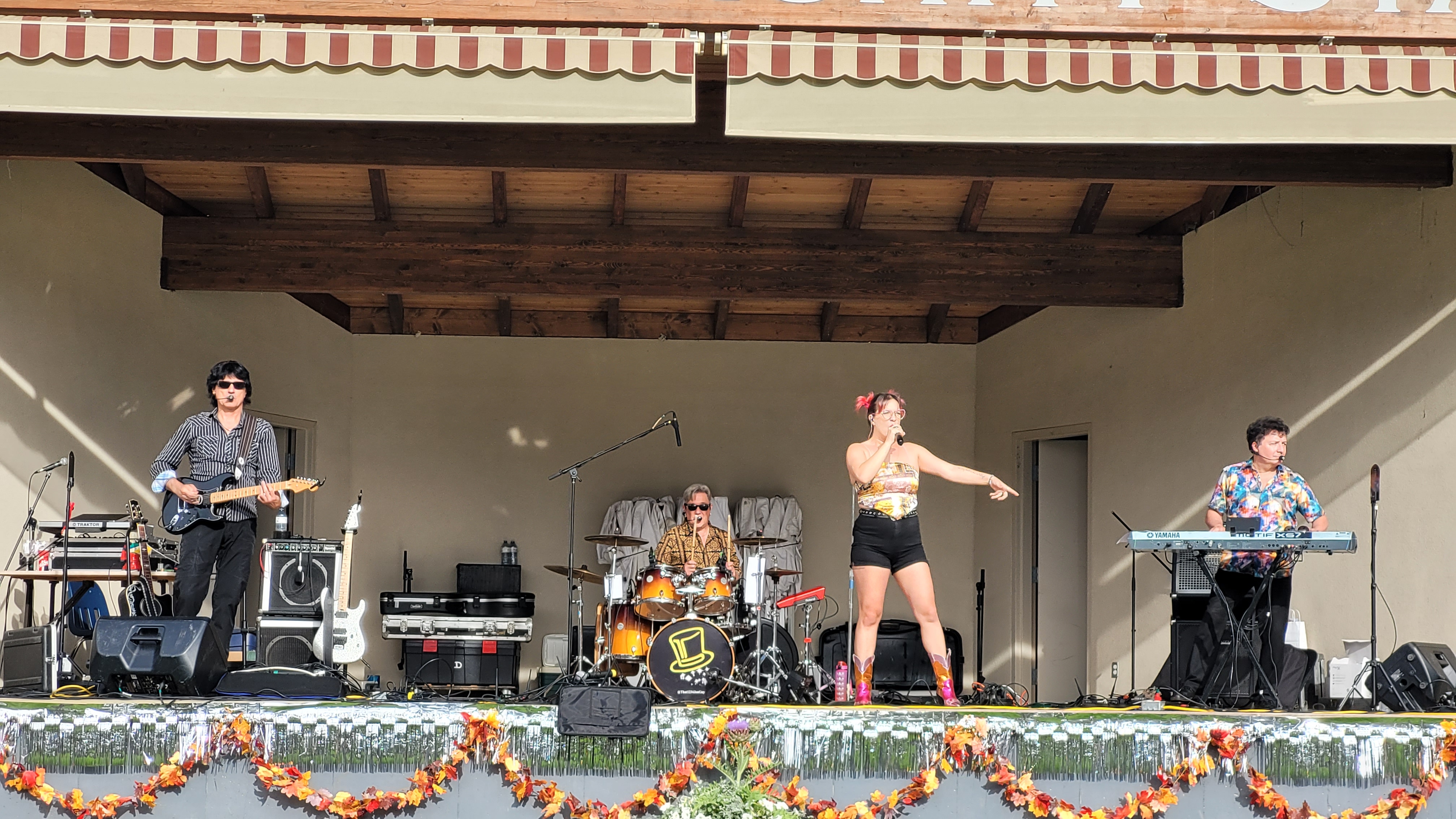 Pop rock tribute band performing live on an outdoor covered festival stage